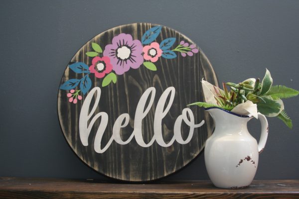 wood sign with floral print that says hello