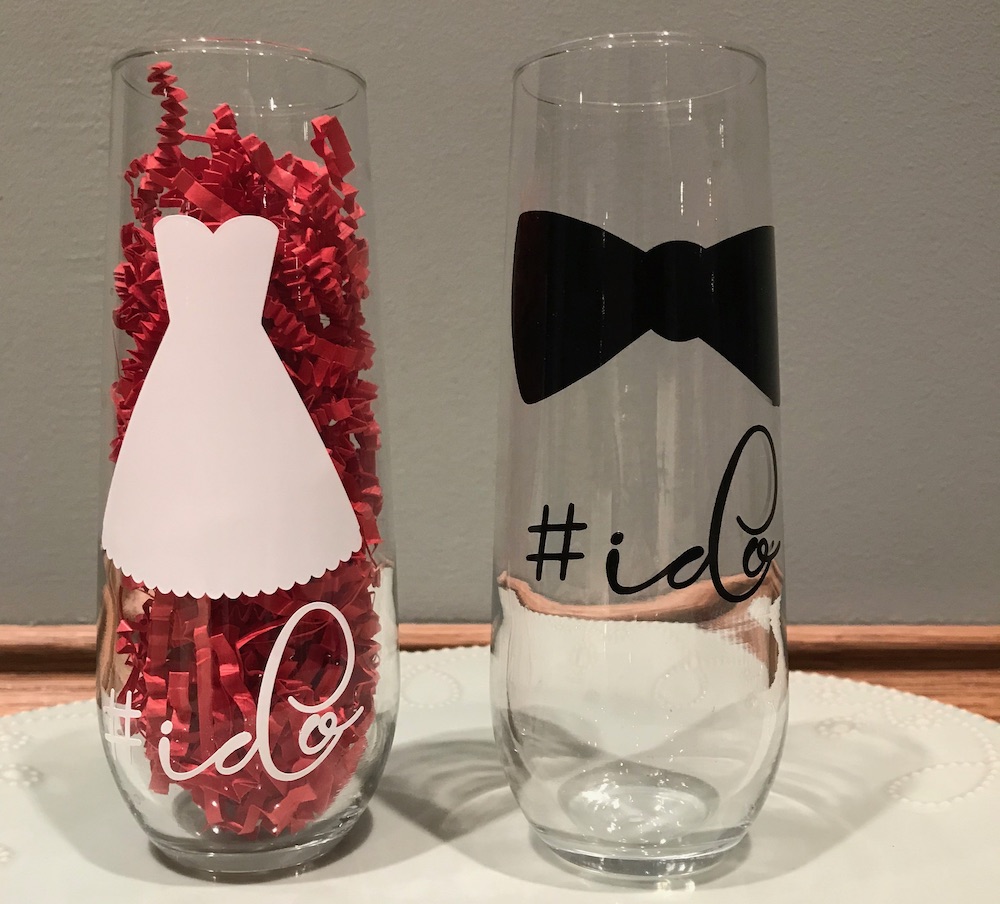 Champagne flutes with a wedding dress and bowtie that say "I do"