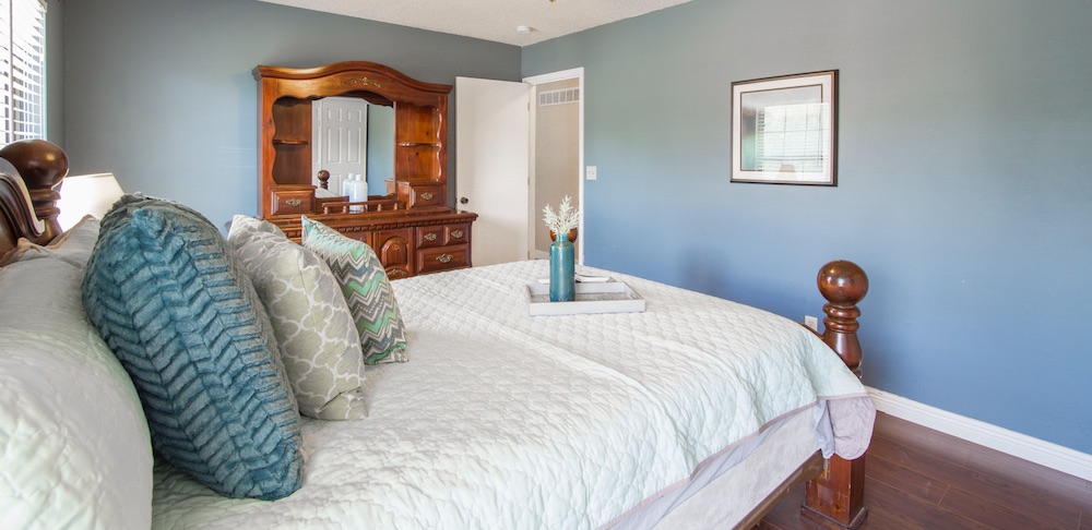 Bedroom with blue walls, white bedding, and throw pillows