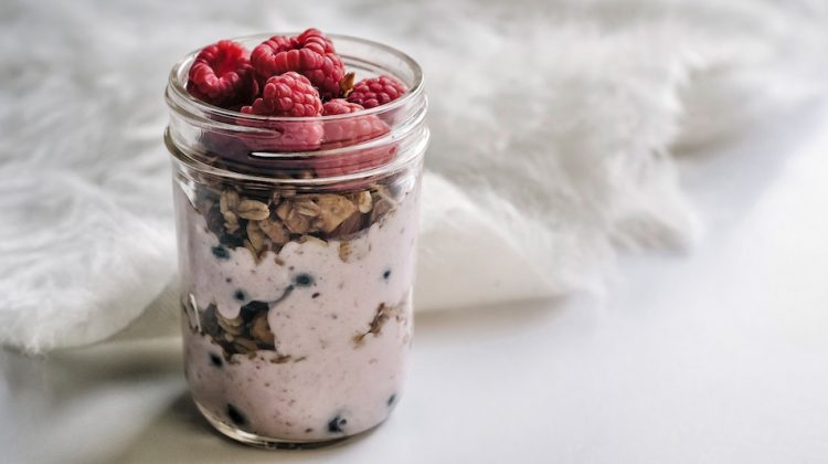 Parfait with raspberries and granola in a glass jar