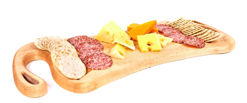 Wood cutting board with cheese, crackers, and meat